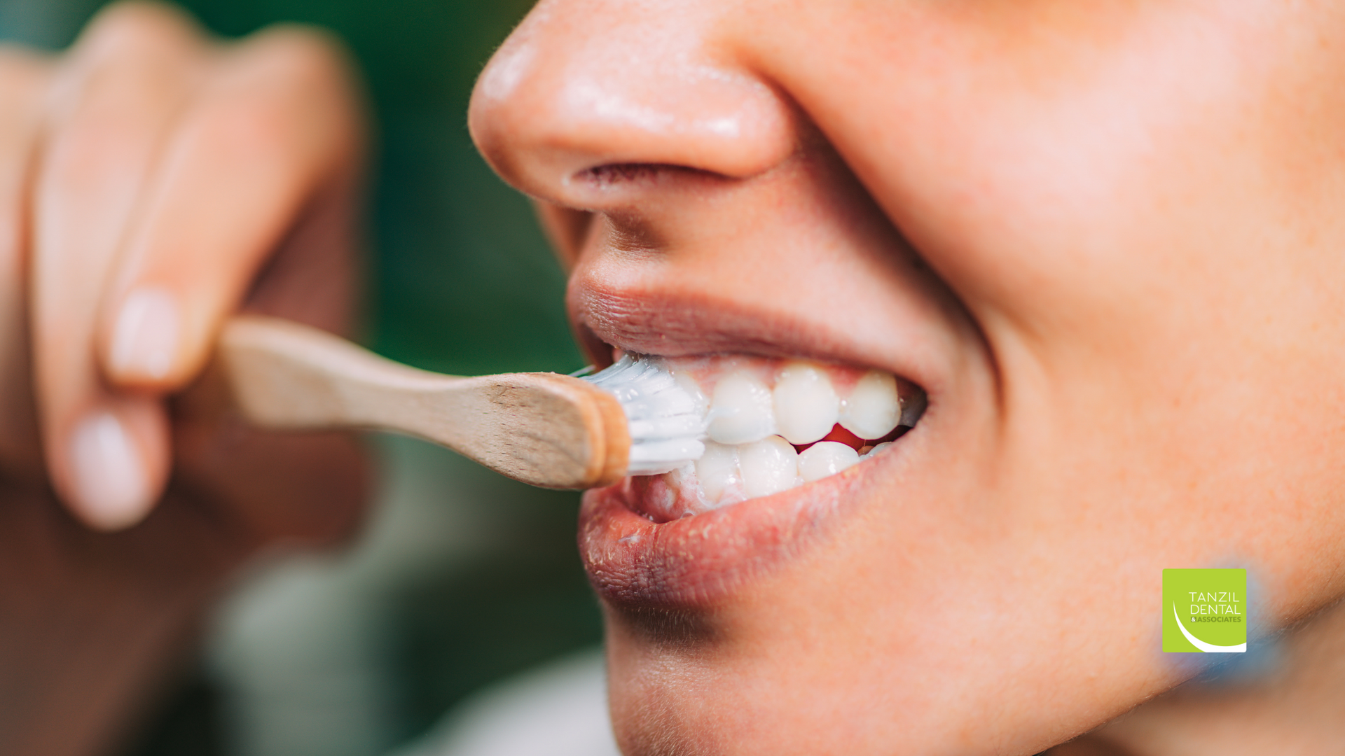 A woman is brushing her teeth with a wooden toothbrush.