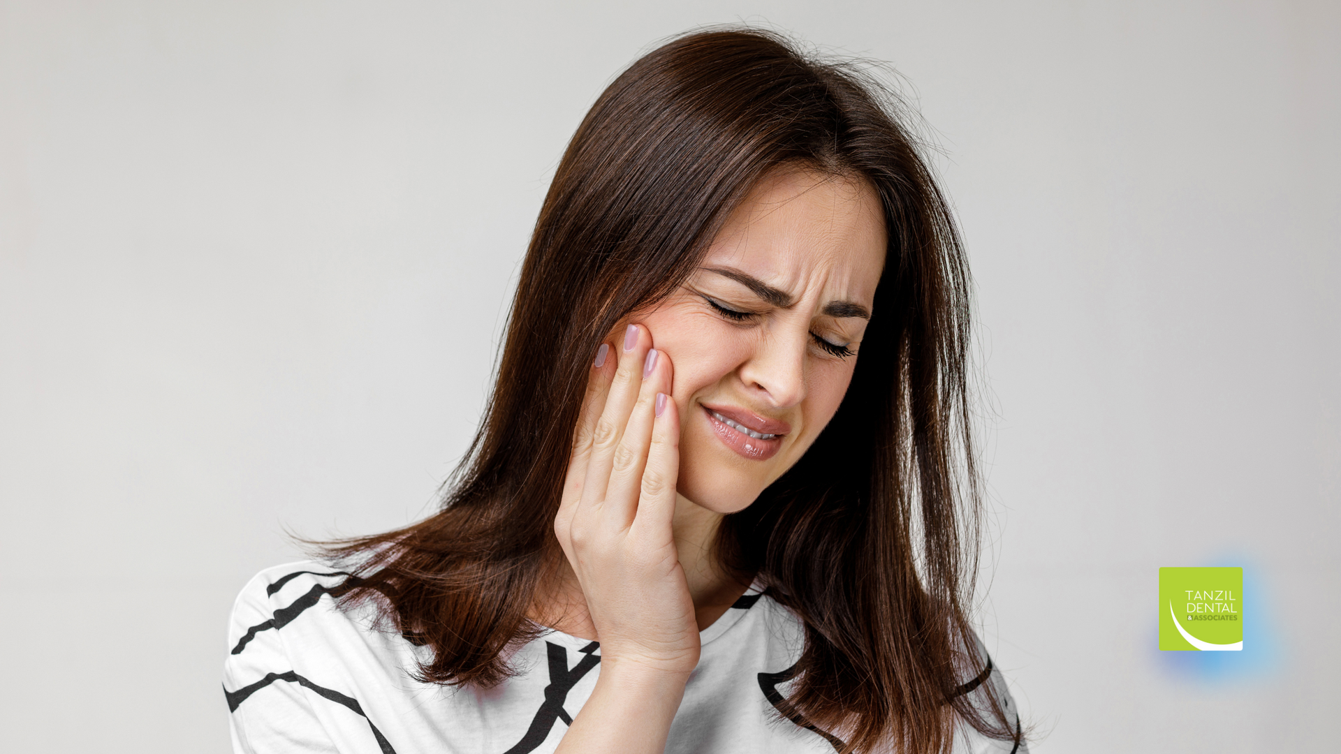 A woman is holding her face in pain because of a toothache.