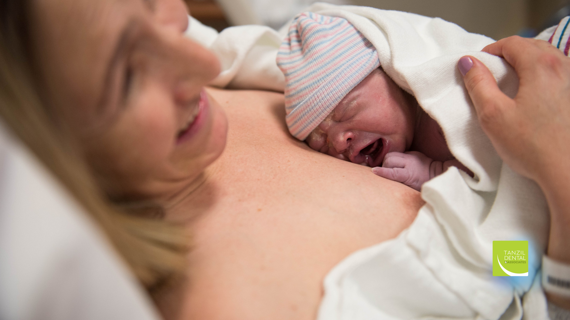 A woman is holding a newborn baby wrapped in a blanket in a hospital bed.