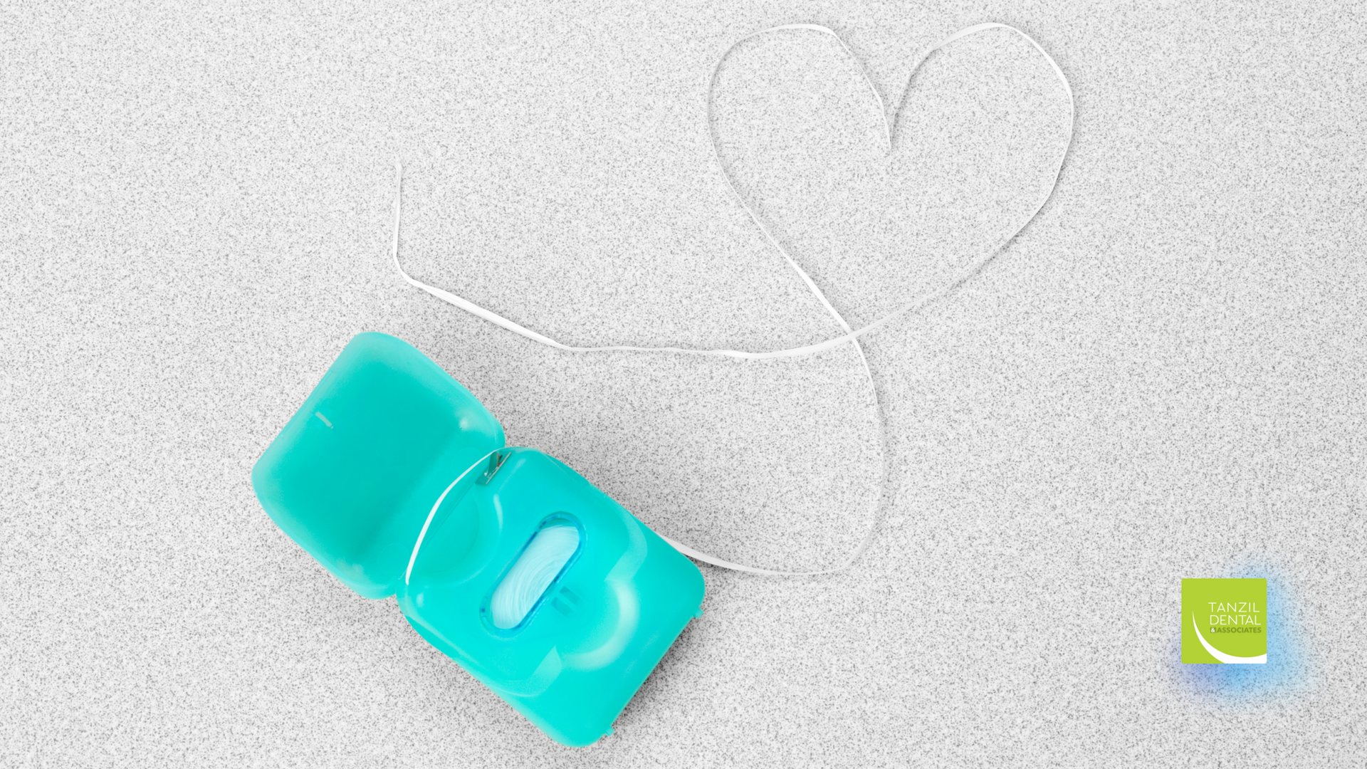A dental floss is sitting on a table next to a heart made of floss.