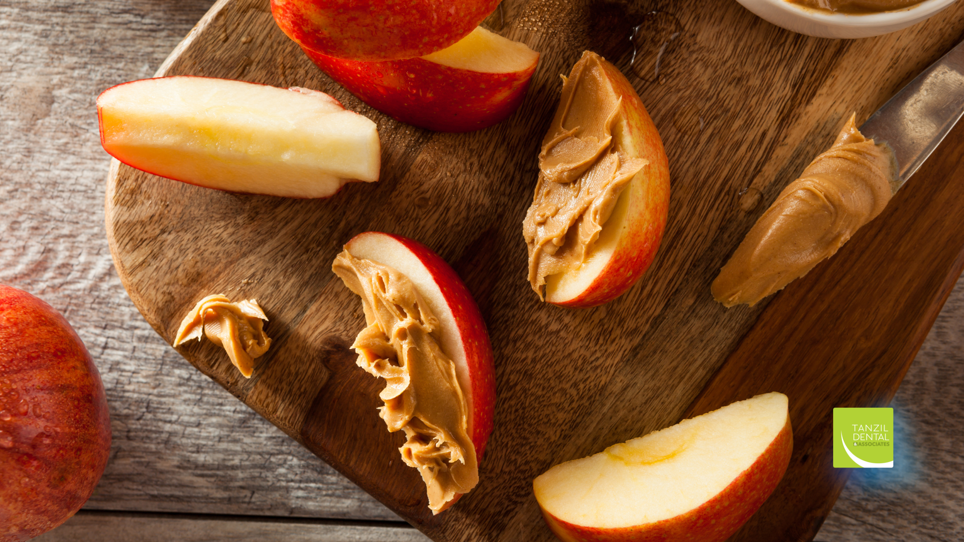 Apple slices with peanut butter on a wooden board.