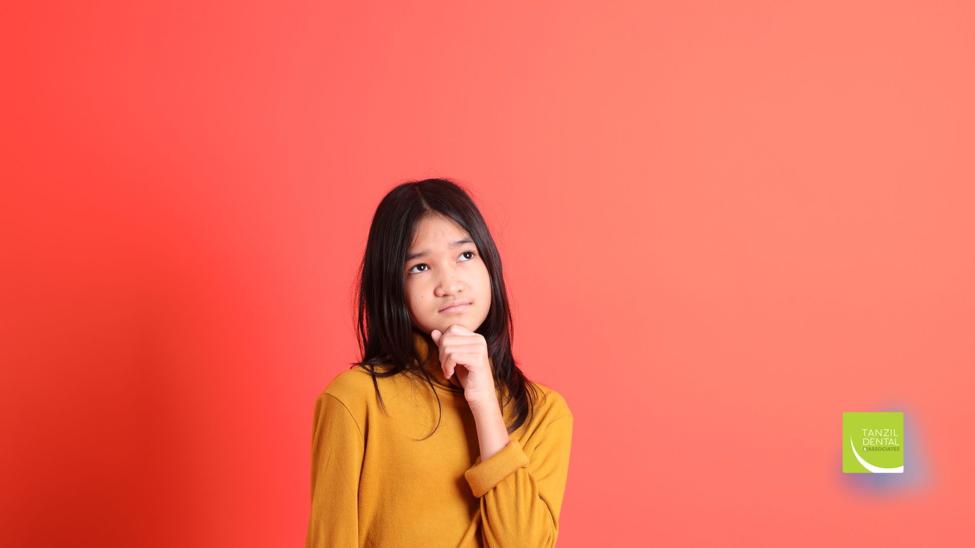 Girl in a yellow shirt looks up thoughtfully, hand on chin, against a red background.