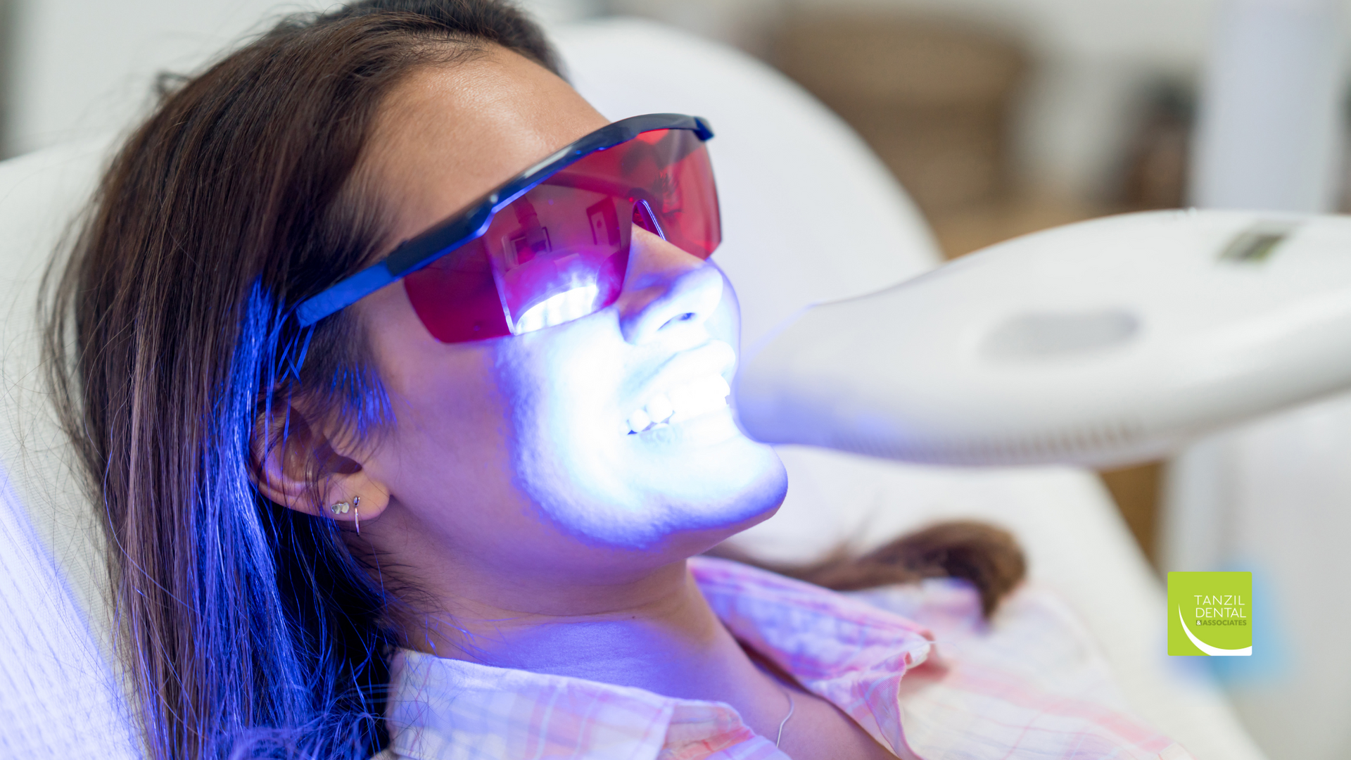 A woman is getting a teeth whitening treatment at a dental office.
