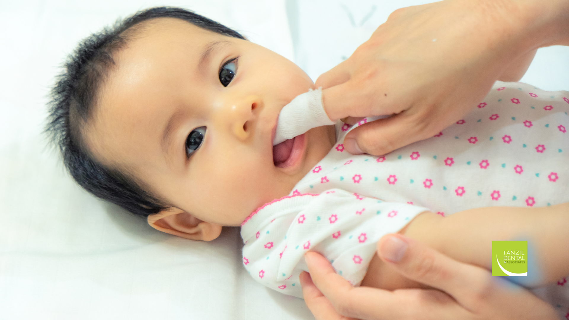 A woman is cleaning a baby 's mouth with a toothbrush.