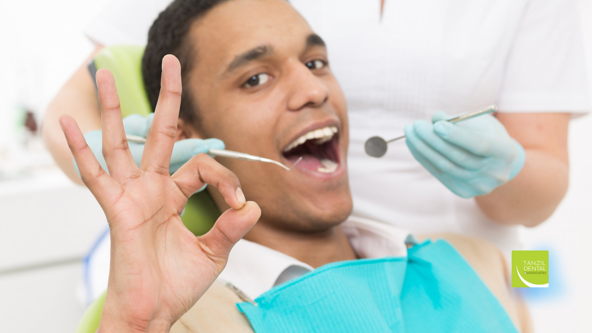 A man is sitting in a dental chair while a dentist examines his teeth.