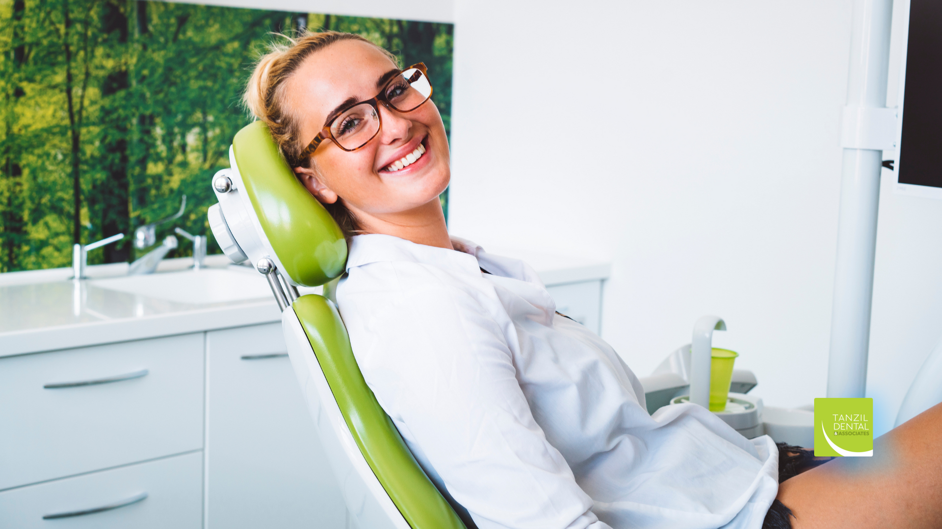 A woman is smiling while sitting in a dental chair.