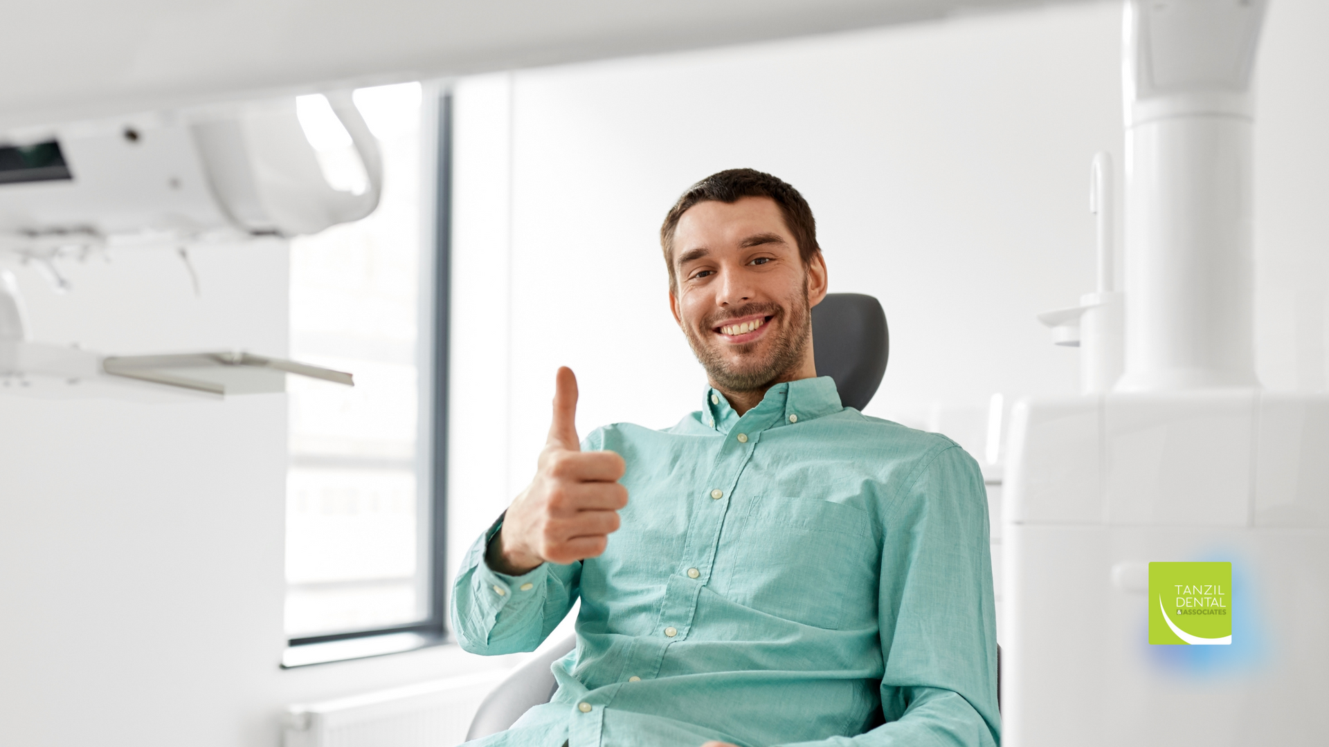Man in dentist chair gives thumbs up. Smiling, seated in a dental office.