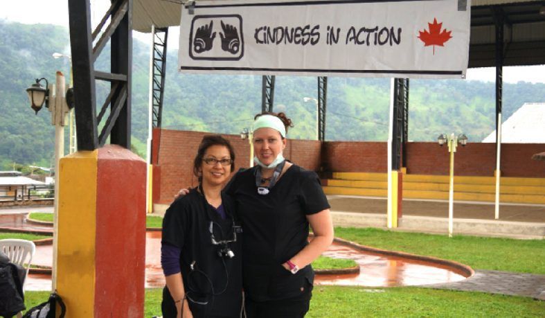 Two women in scrubs stand under a 