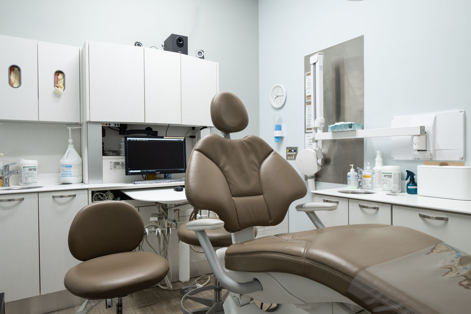 Dental office examination room with a dental chair and white cabinetry.