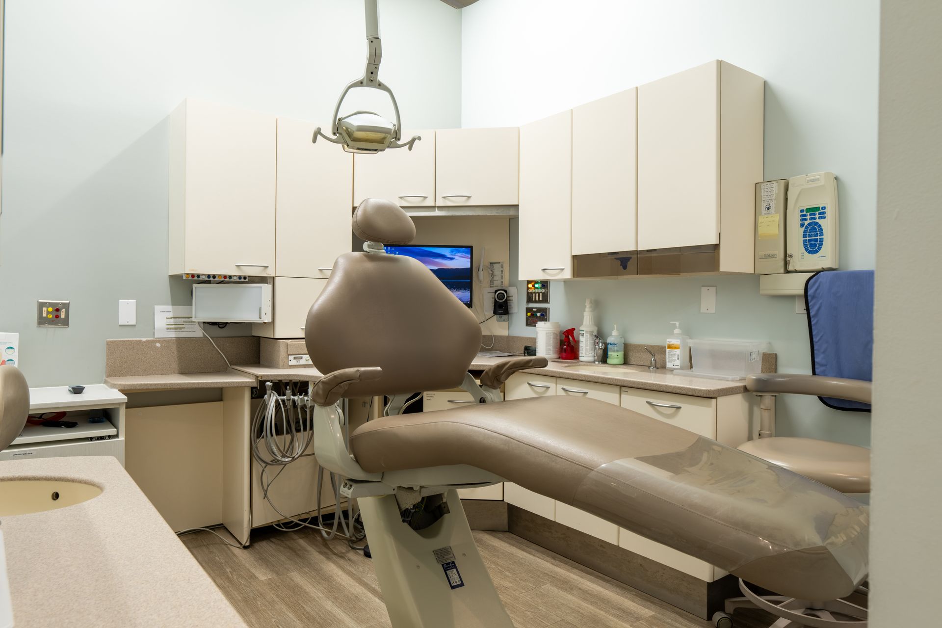 Dental operatory with chair, cabinets, and equipment. Neutral color palette.