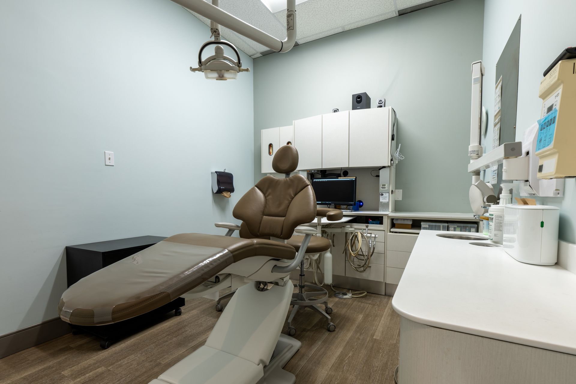 Dental operatory room with chair, light, cabinets, and a counter.