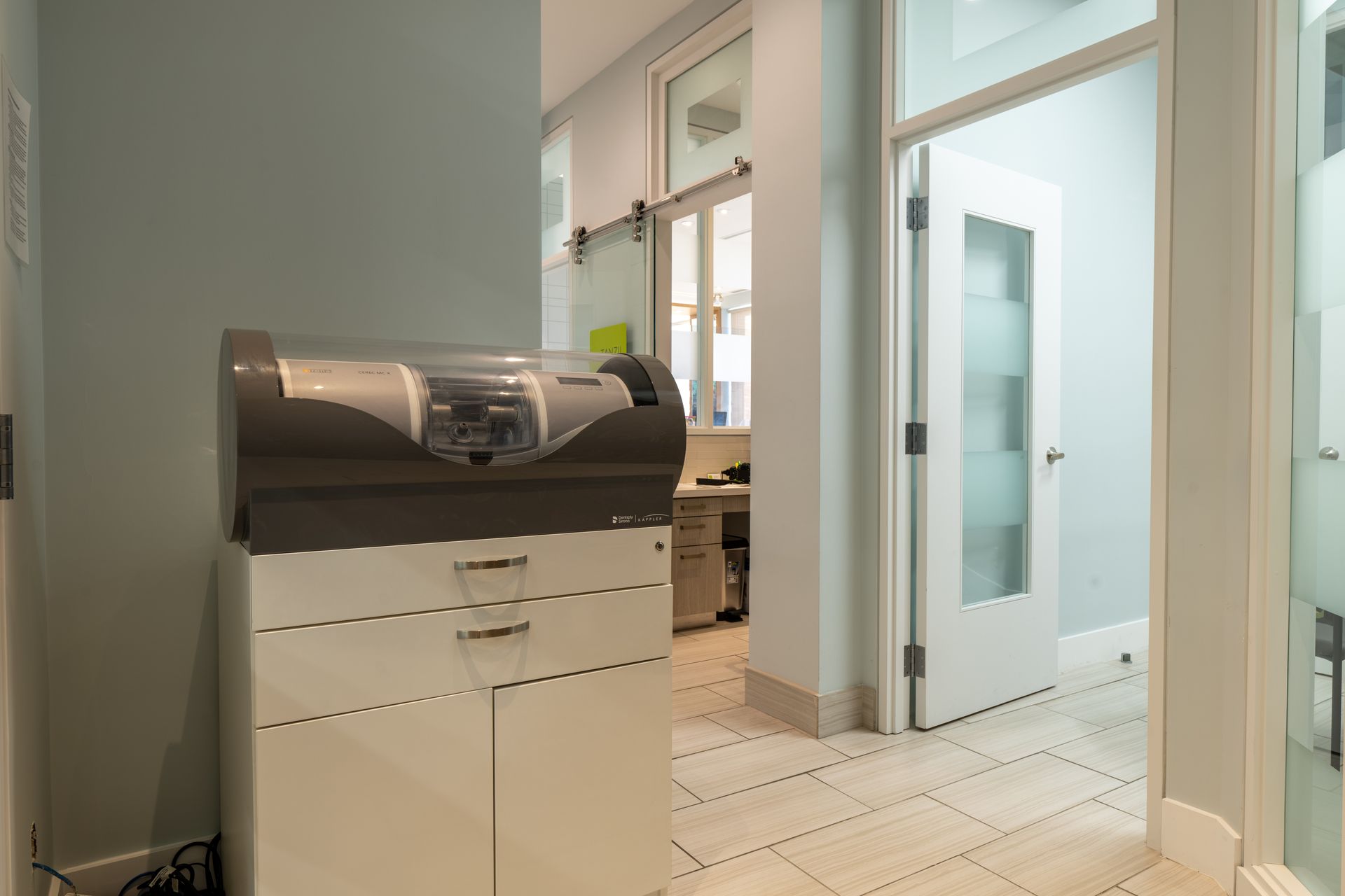Dental office interior with milling machine, hallway, and frosted glass door.