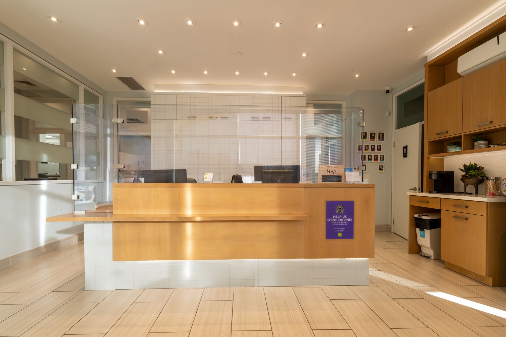 Reception desk in a brightly lit office with light wood and light blue walls.