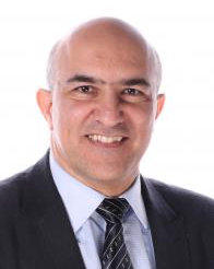 Smiling bald man in a dark suit and striped tie against a white background