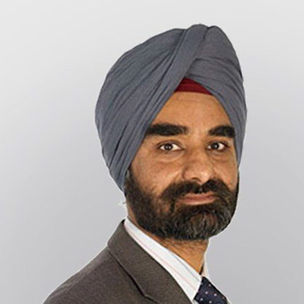 Portrait of a man in a gray turban and suit against a light gray background