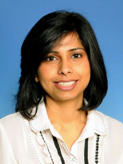Portrait of a smiling woman with shoulder-length black hair against a blue background