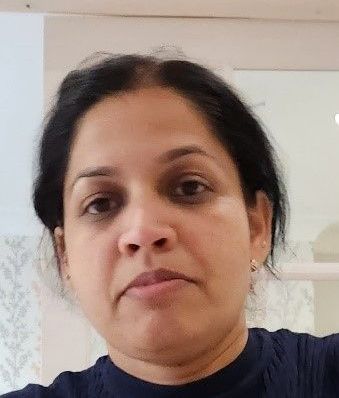 Close-up of a person with dark hair indoors, looking at the camera with a neutral expression.