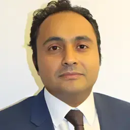 Headshot of a person in a blue suit, white shirt, and dark tie against a plain background