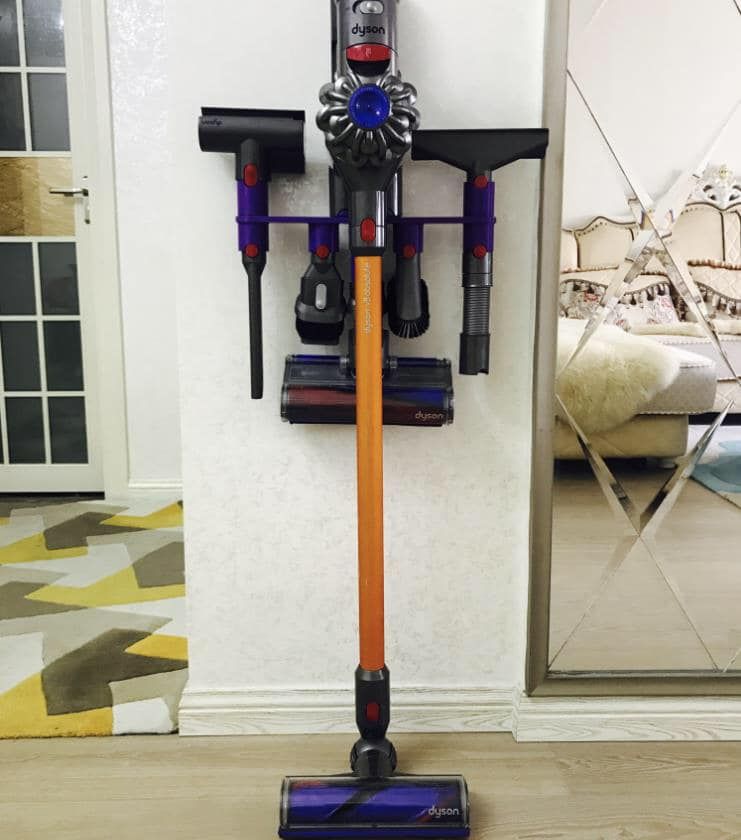 Wall-mounted Dyson vacuum station with attachments in a modern home interior