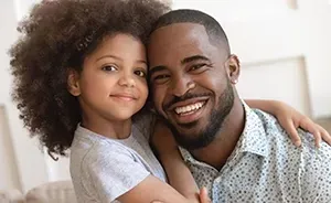 Smiling adult and child embracing on a couch in a bright room