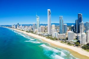 Aerial View of a City With a Beach and a City SkylineTree Branch is Laying on a Sandy Beach With a Sailboat in the Distance — Supercare Gold Coast in Broadbeach, QLD