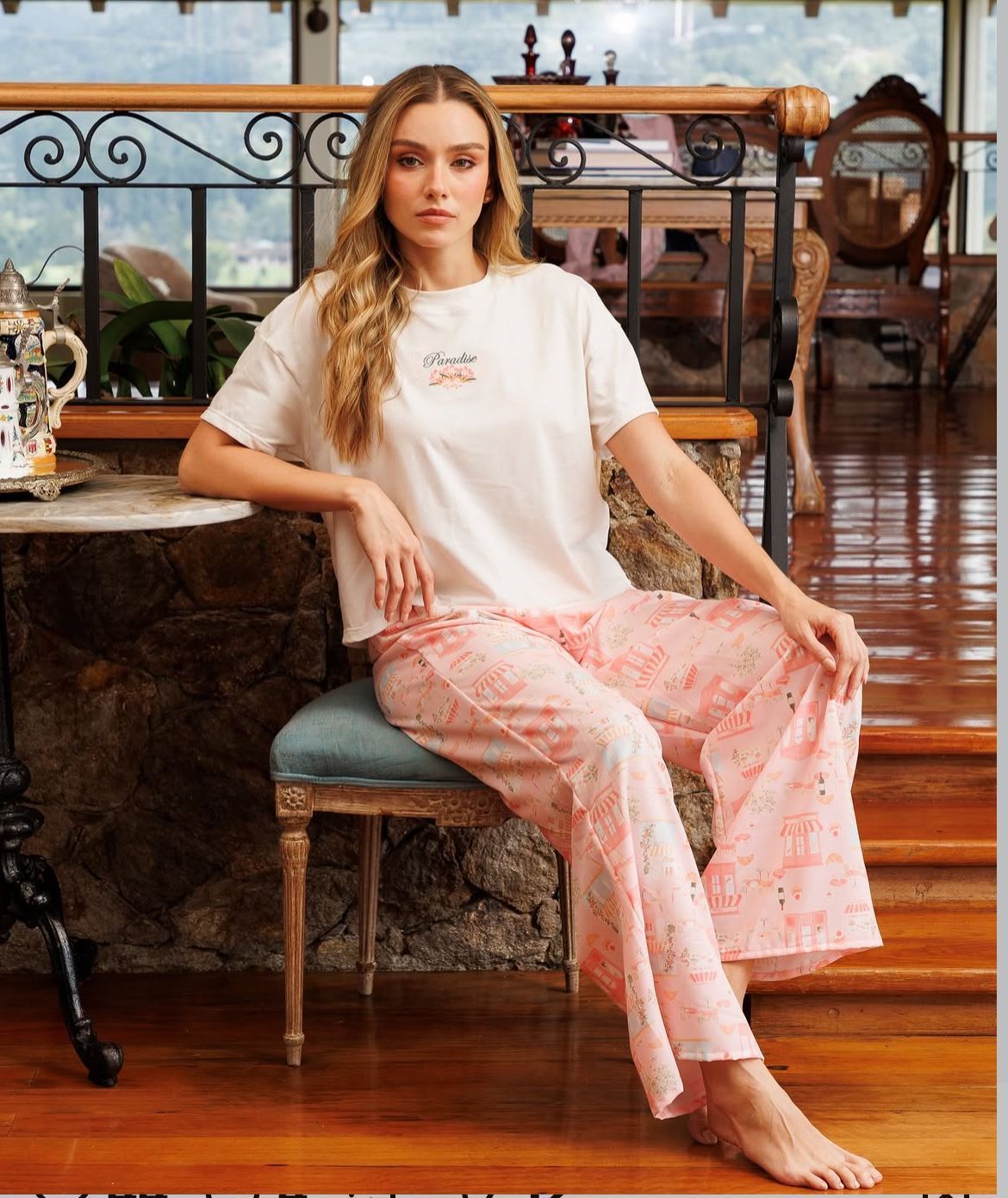 Mujer sentada en unos escalones, con camiseta blanca y falda rosa, mirando a la cámara.