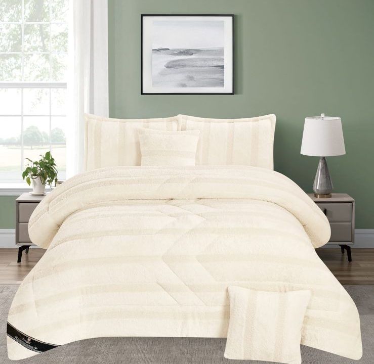 Edredón acolchado color crema sobre una cama en un dormitorio de color verde suave con mesitas de noche .