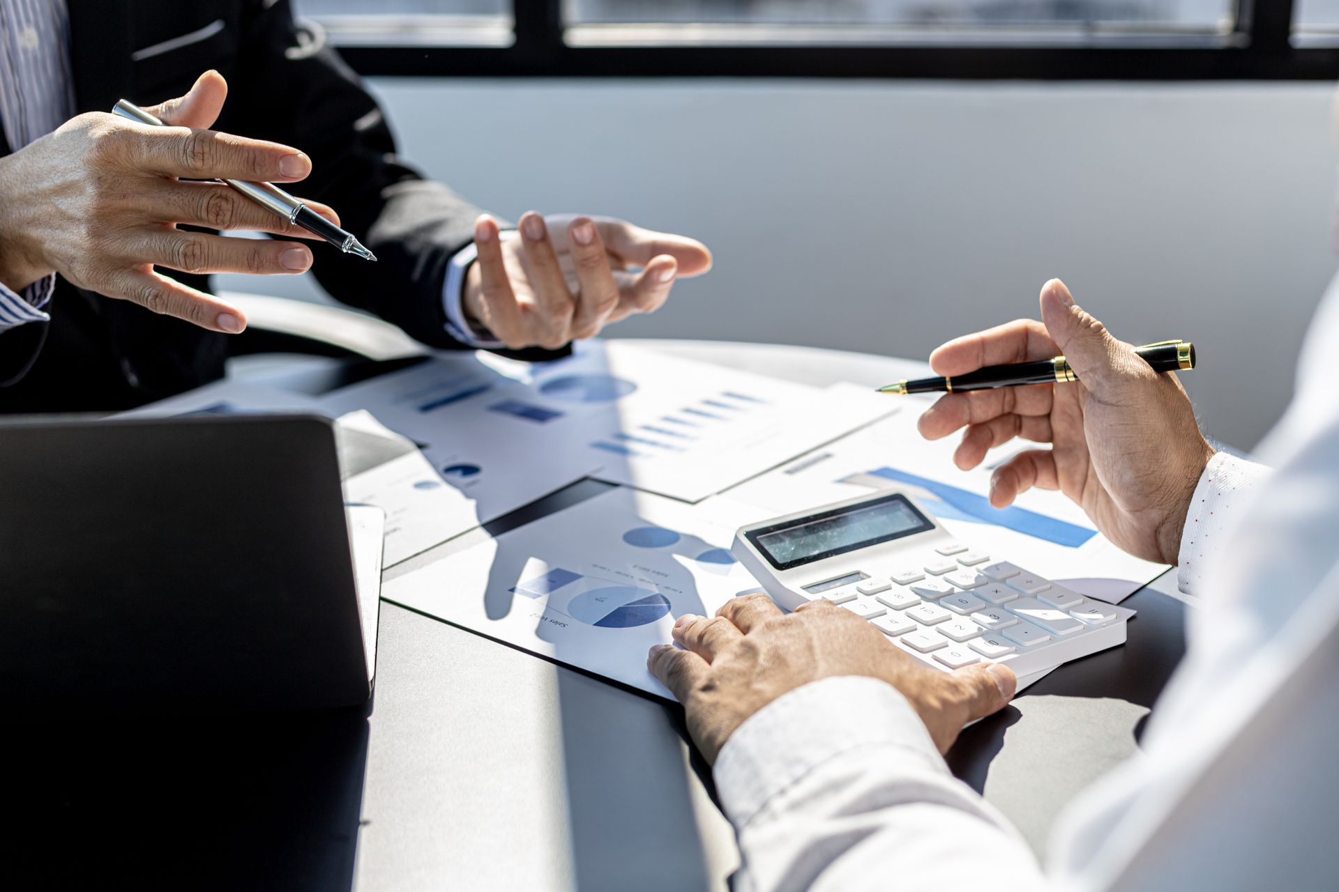 People in a business meeting reviewing charts and numbers on a bright conference table