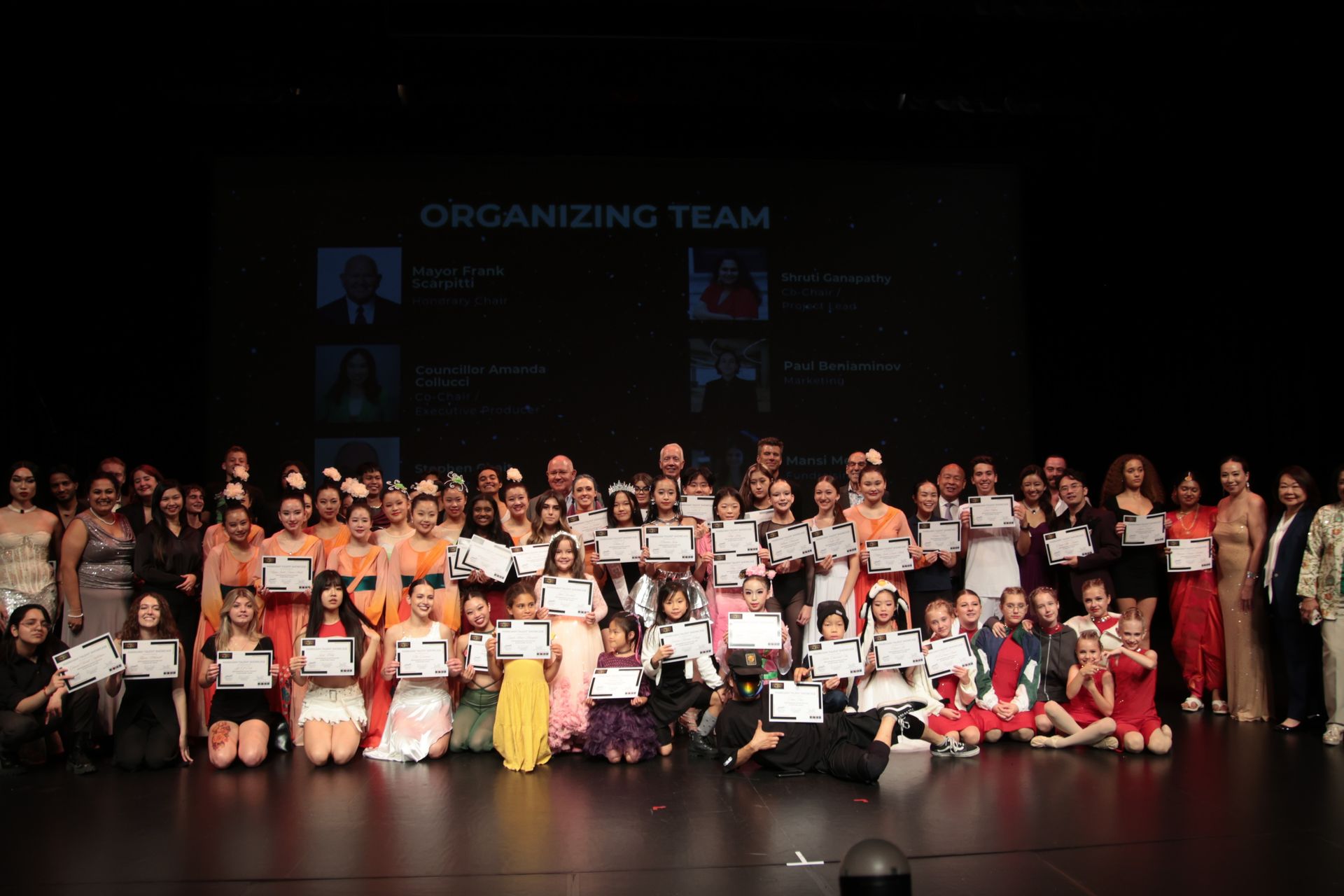 A large group of people are posing for a picture on a stage.