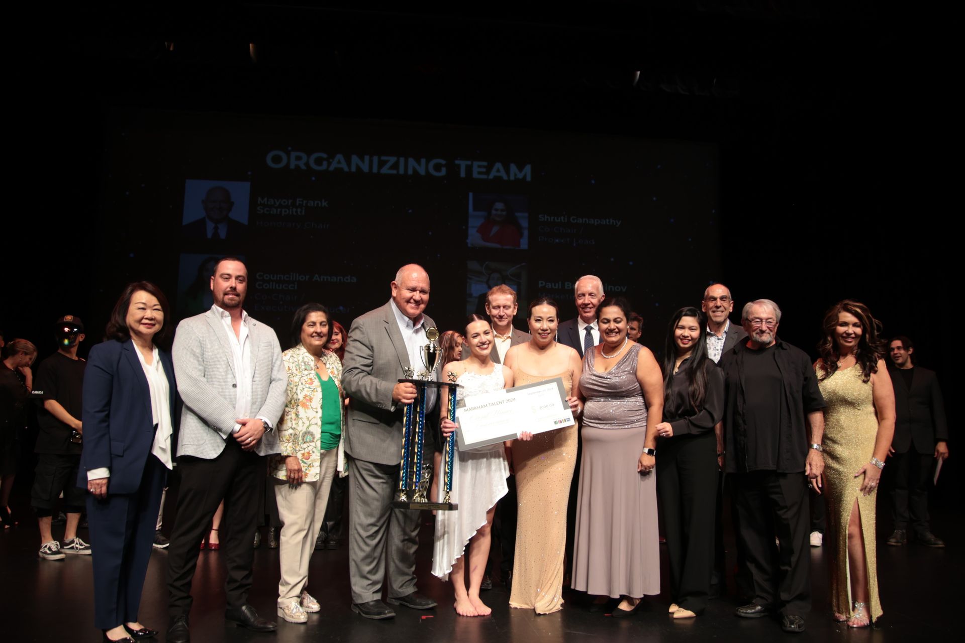 A group of people are standing on a stage holding a trophy.