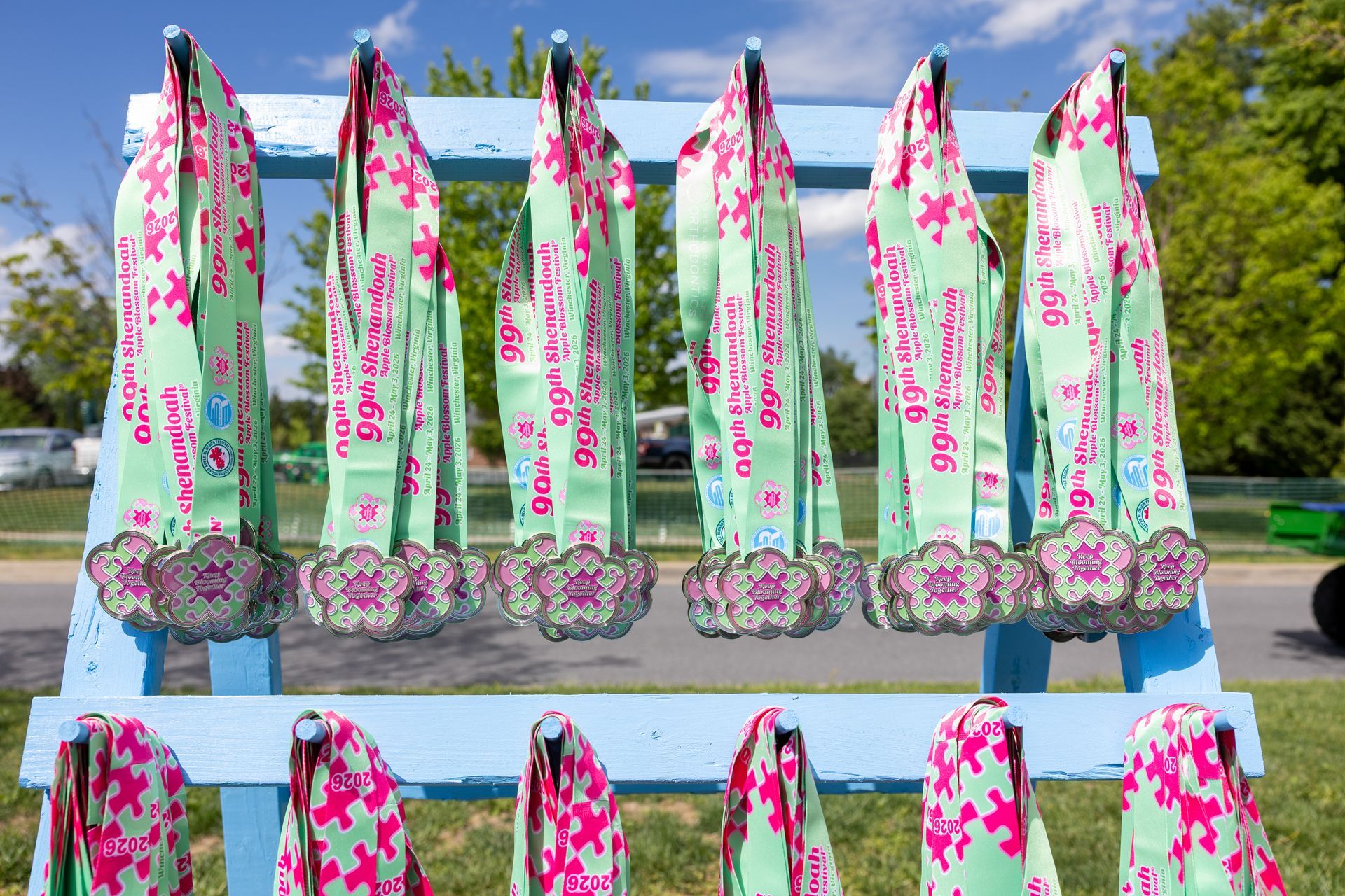 Colorful floral beach umbrellas lined up outdoors on display racks under a sunny sky