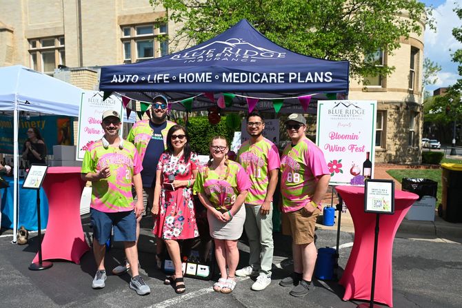Group of people in bright pink and green shirts at an outdoor health fair booth under a blue canopy. Blue Ridge