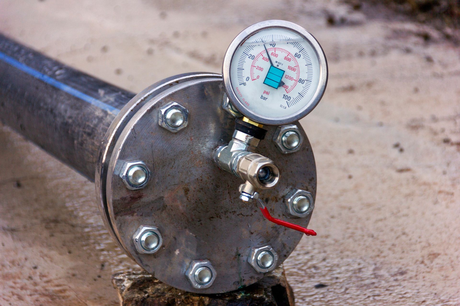 A pressure gauge is sitting on top of a metal pipe.