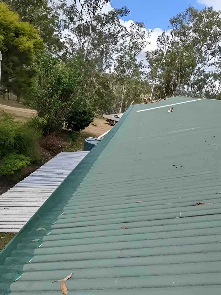 A Green Roof With Trees in the Background and a Wooden Deck in the Foreground — All-Clear Gutter Guard NQ in Gordonvale, QLD