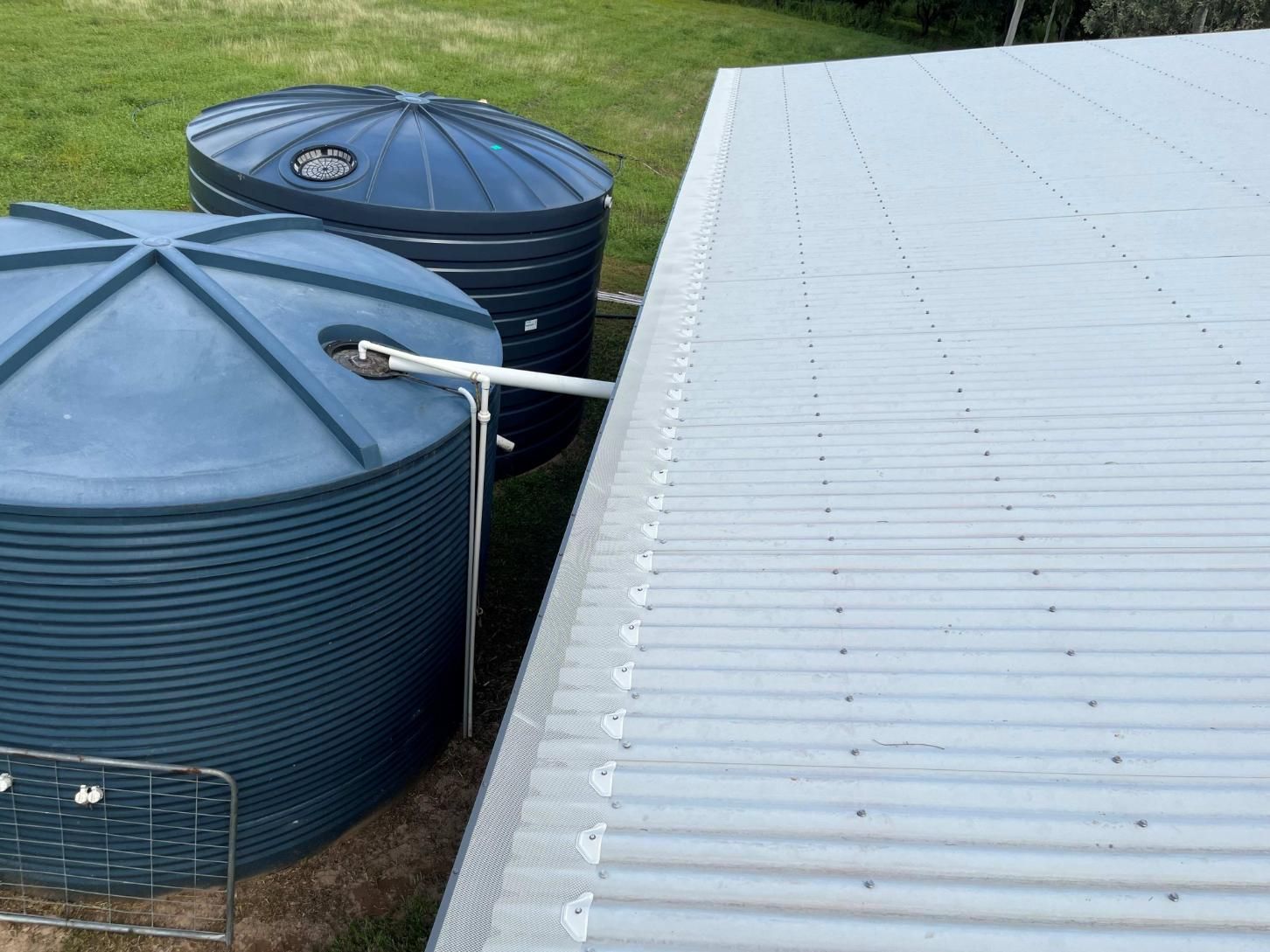 Two Blue Water Tanks Are Sitting Next to a White Roof — All-Clear Gutter Guard NQ in Palm Cove, QLD