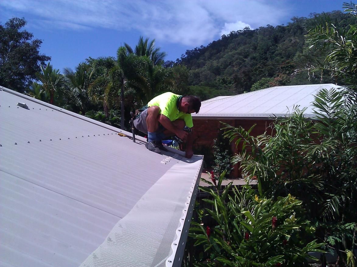 A Man is Working on the Roof of a House — All-Clear Gutter Guard NQ in Tablelands, QLD