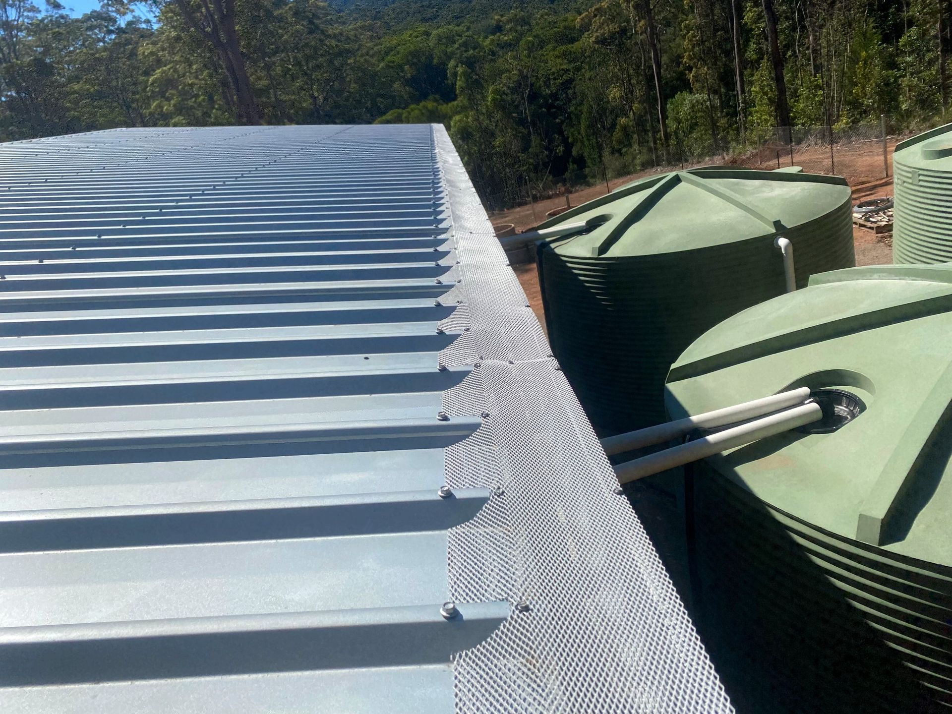 A Roof with A Gutter and Water Tanks on It — All-Clear Gutter Guard NQ in Gordonvale, QLD