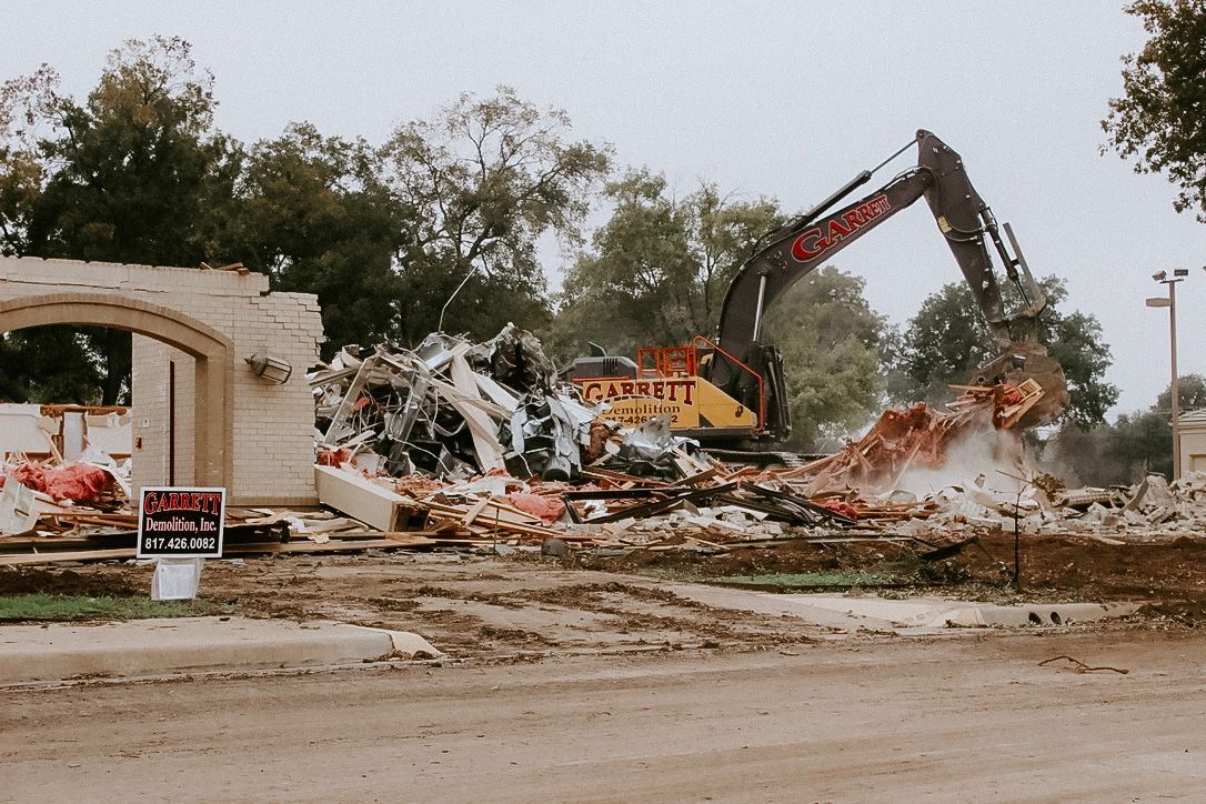 A large yellow excavator is demolishing a house.