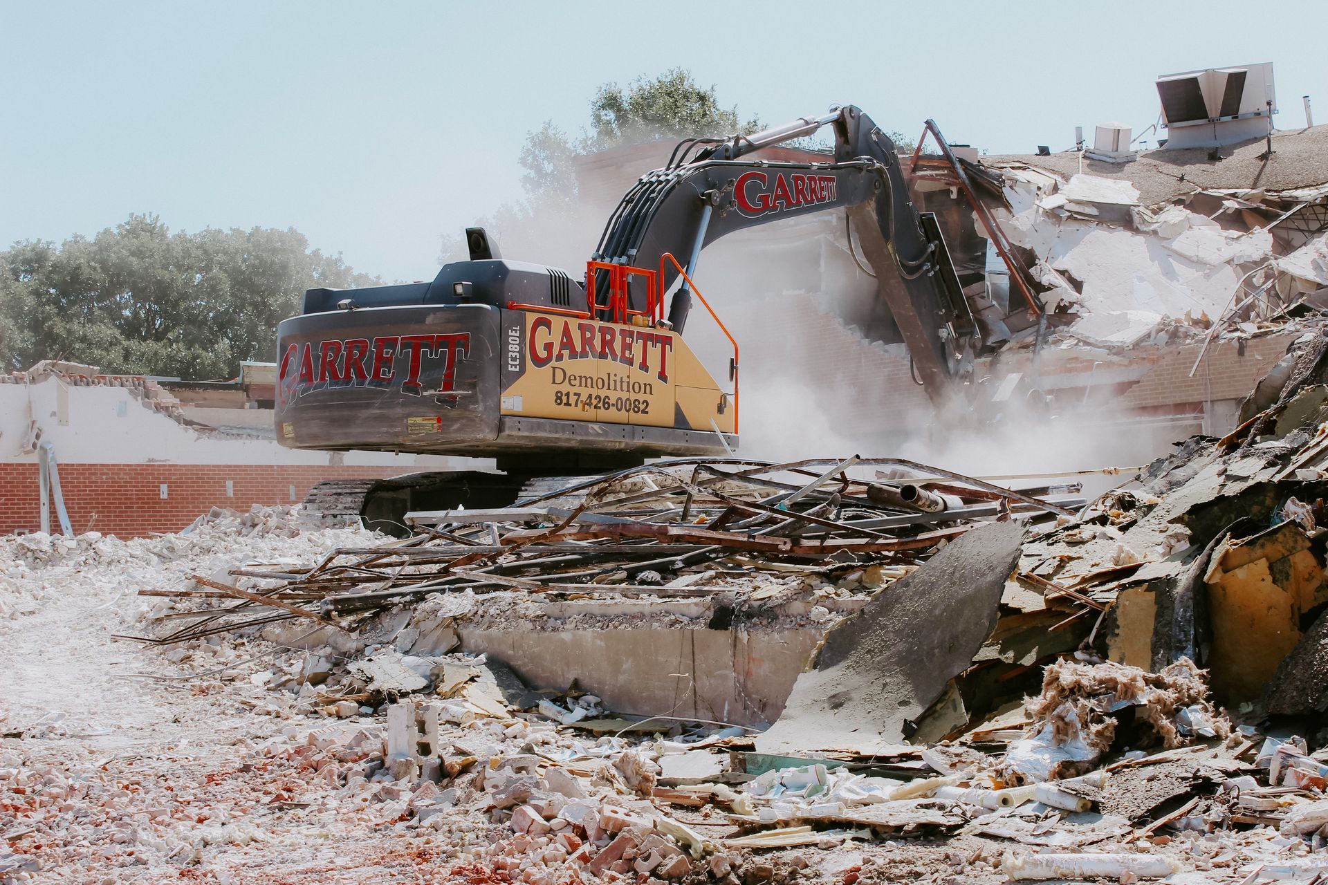 A large excavator is demolishing a building that says ' garrit ' on the side