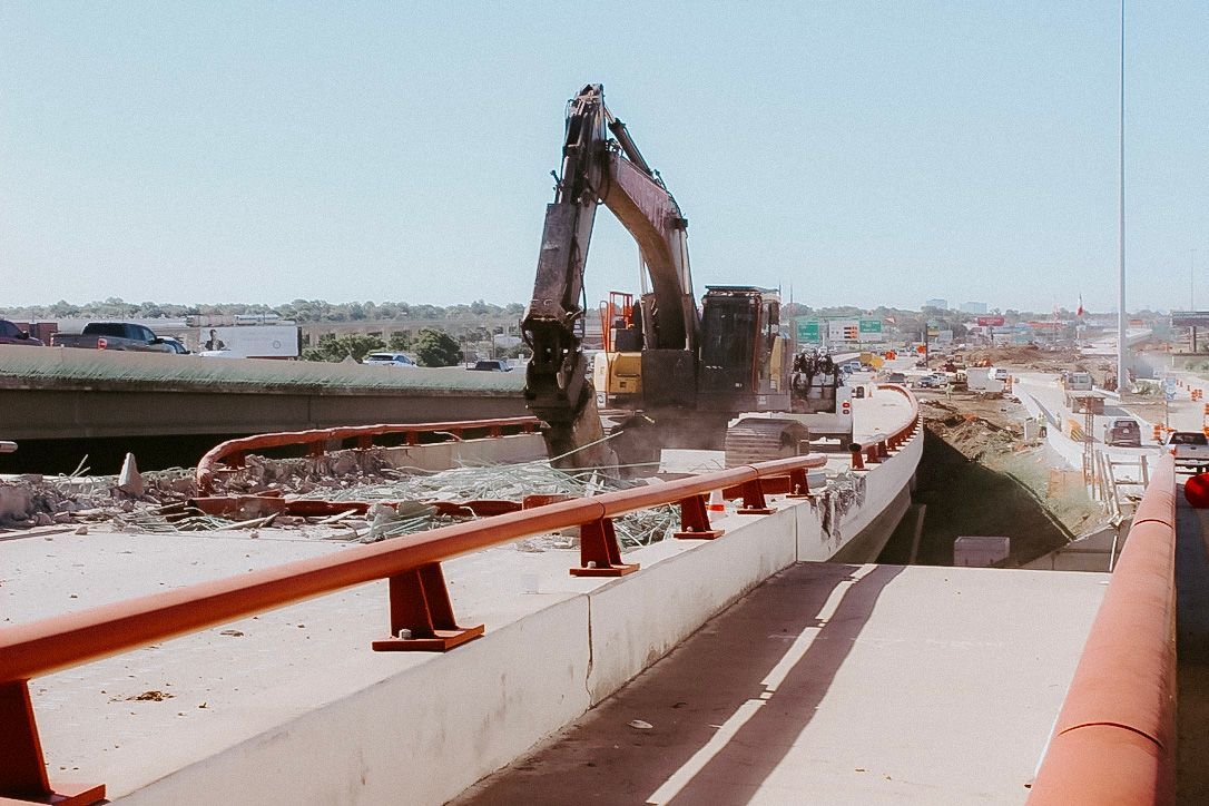 A large excavator is being used to demolish a bridge