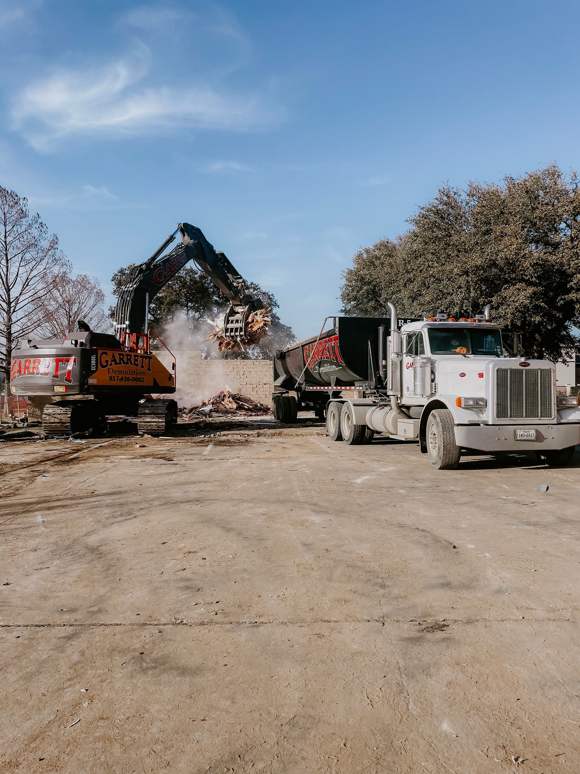 A truck is driving down a dirt road next to a bulldozer.