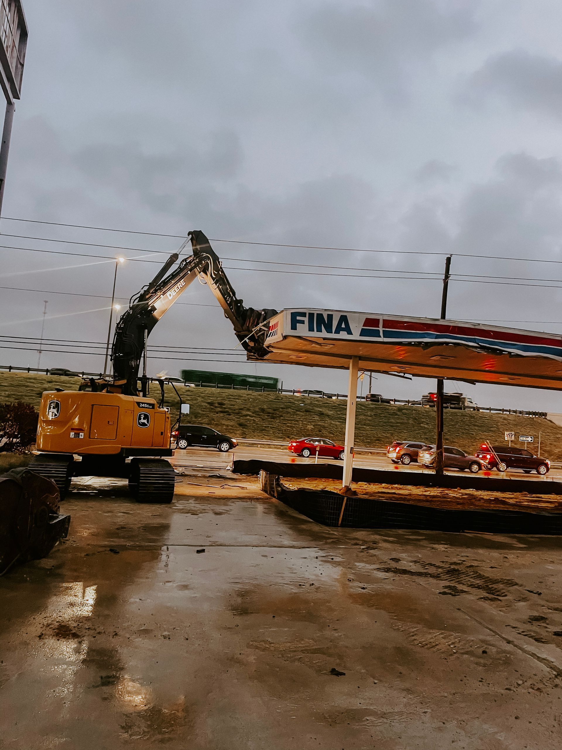 A yellow excavator is demolishing a building that says fina