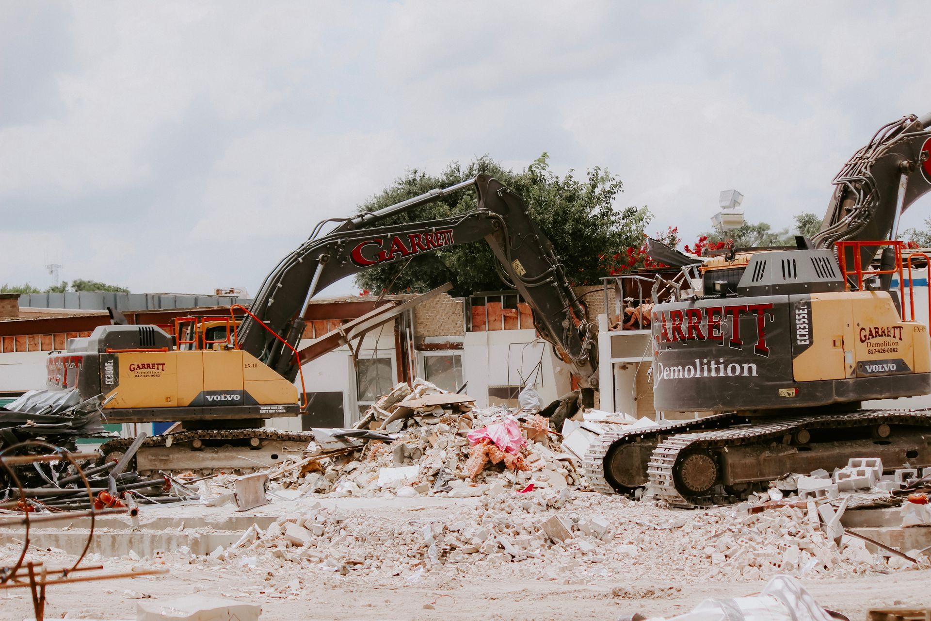 Two bulldozers are demolishing a building on a construction site.