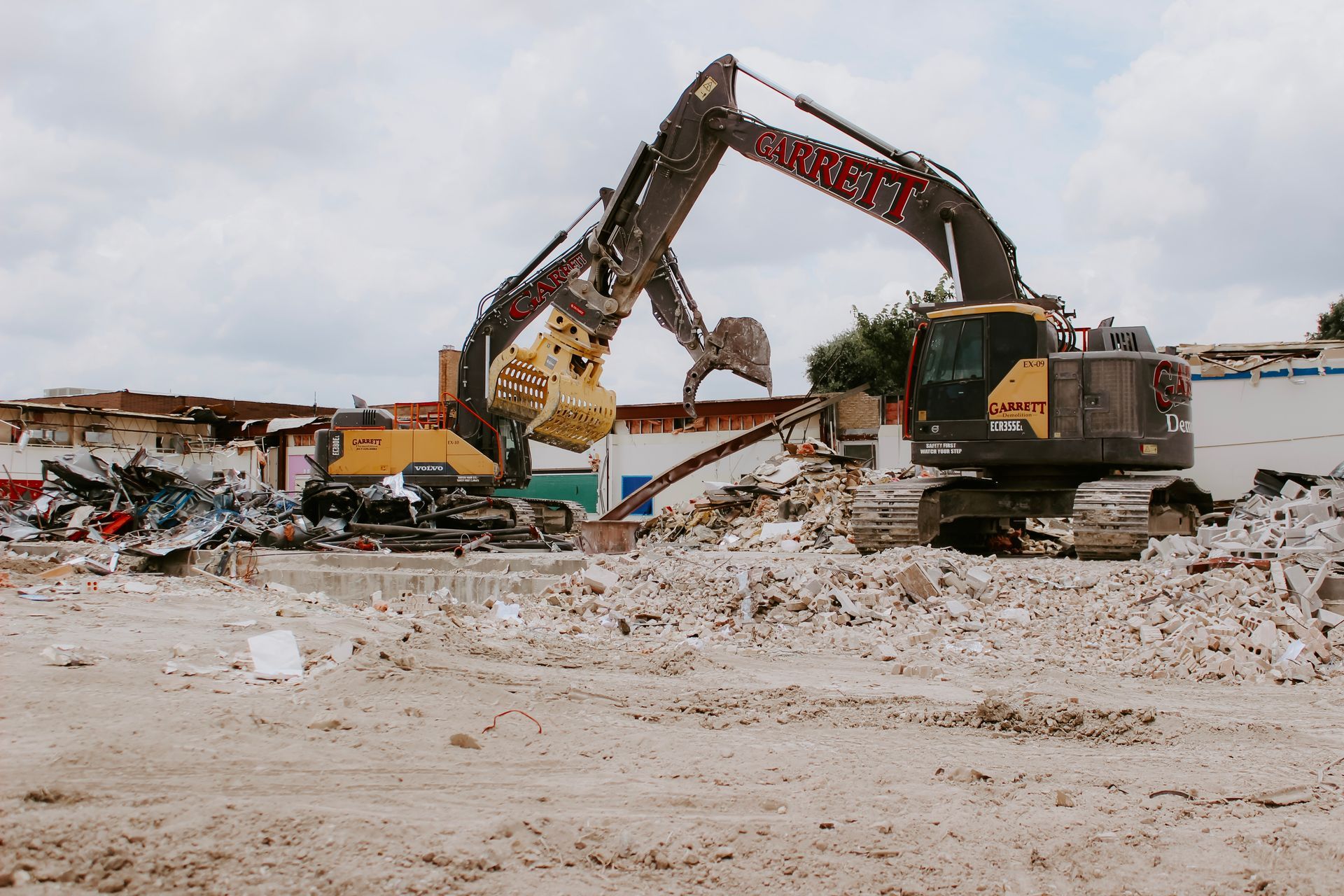 A large excavator is demolishing a building on a construction site.