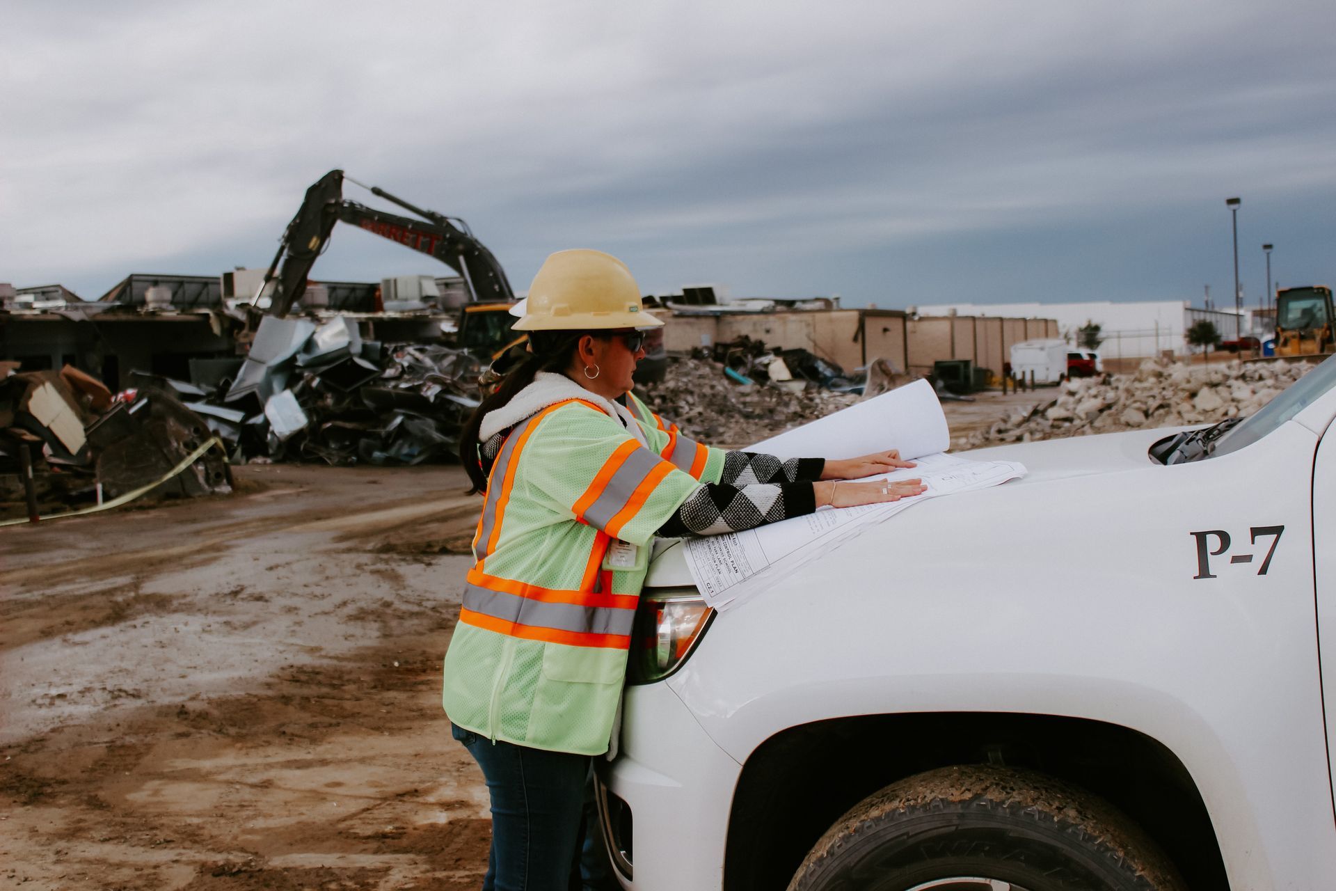A woman in a hard hat is standing next to a white truck.