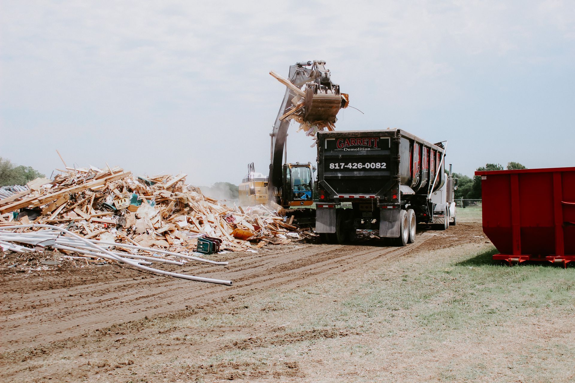 A dump truck is being loaded with a pile of wood.