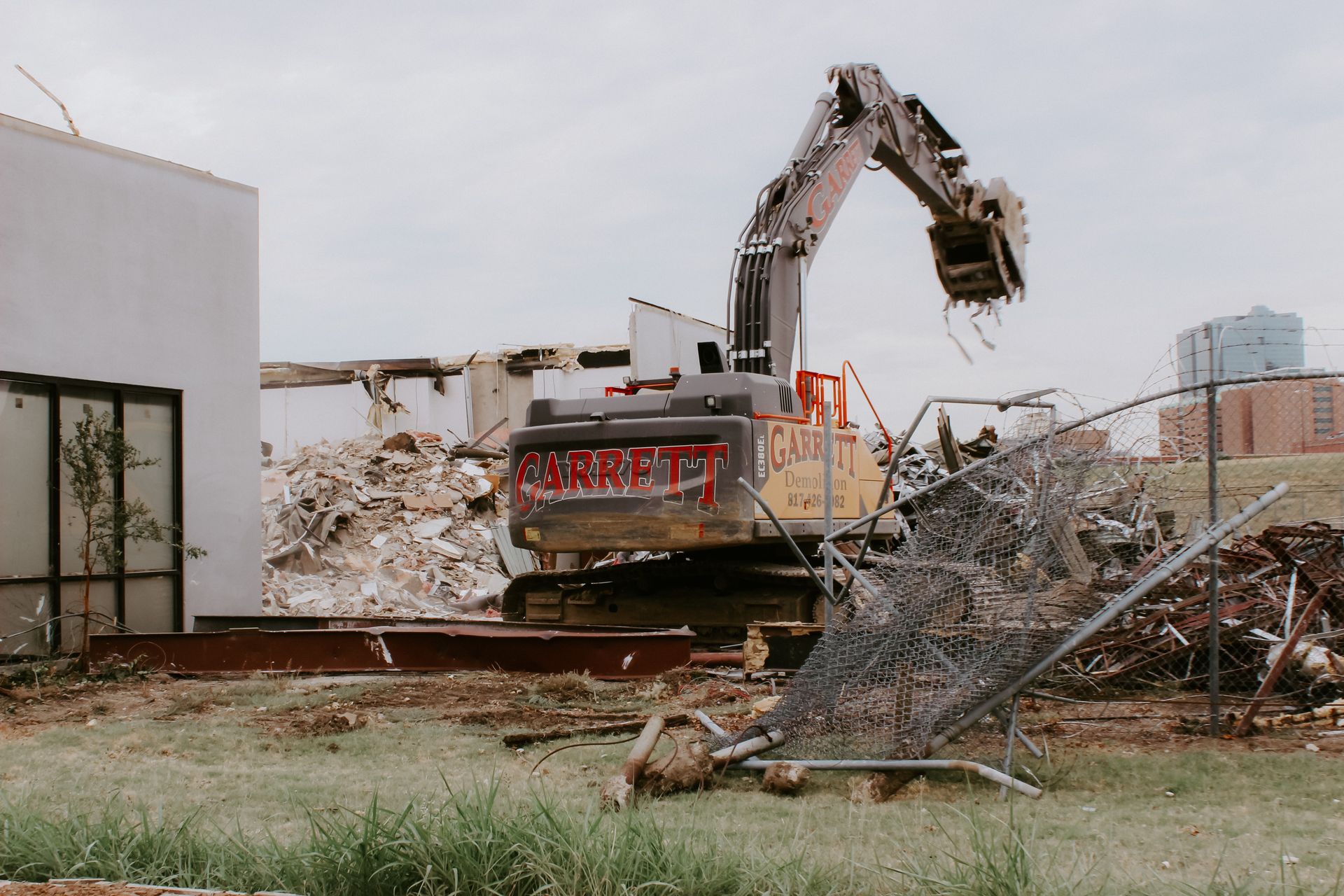 a large excavator is demolishing a building in a field .
