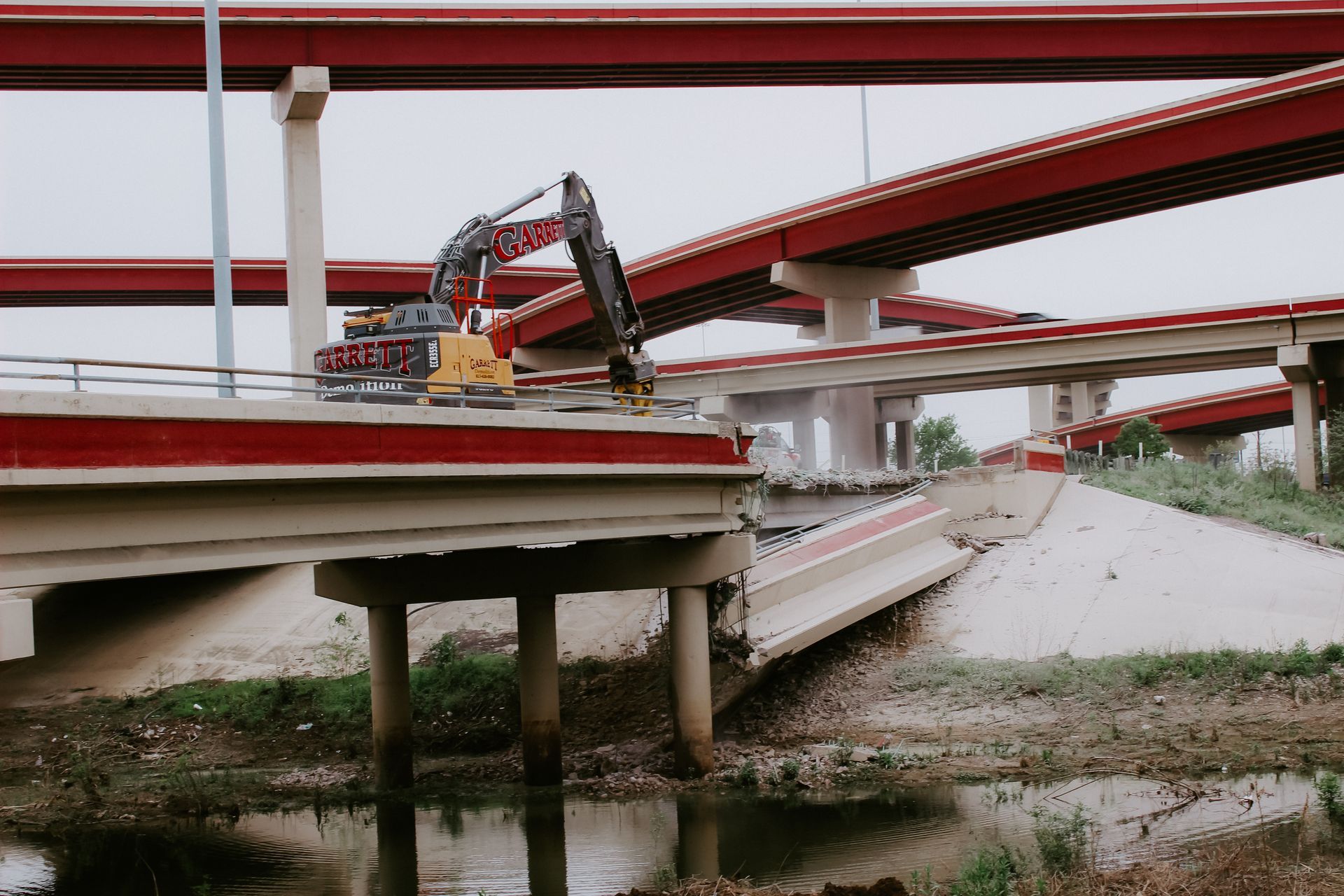 A construction vehicle is working on a bridge over a river.