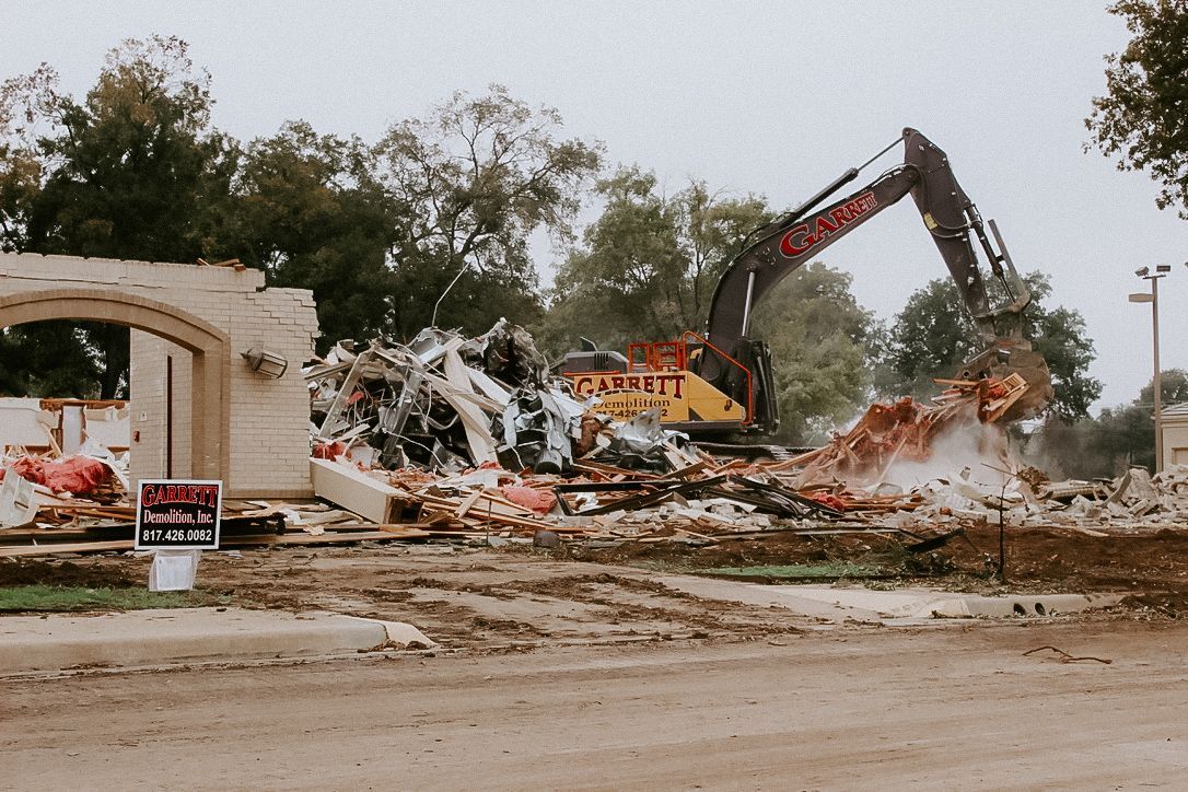 A large yellow excavator is demolishing a building.