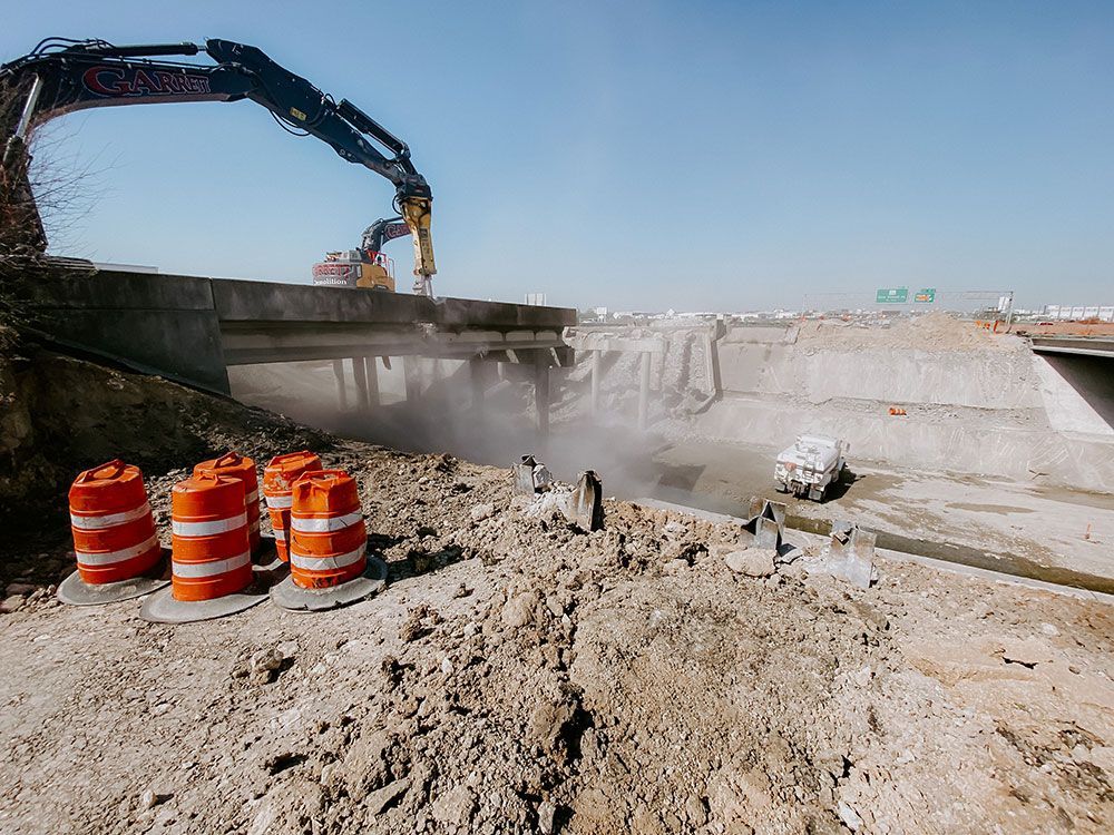A construction site with orange and white traffic cones and a crane.